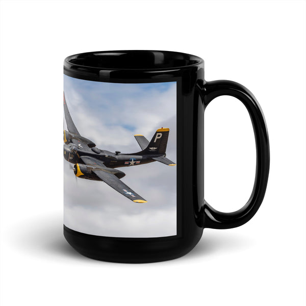 A black ceramic coffee mug with a split design featuring an aerial photograph of an A-26 Invader aircraft on one side.