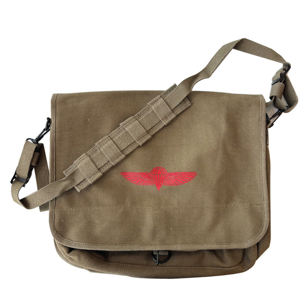 A canvas messenger bag with a red paratrooper emblem on the front, featuring a shoulder strap and a flap closure.  Available in Olive, Khaki, or Black