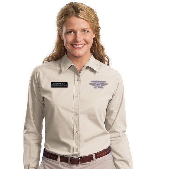 A woman wearing a beige shirt with a name tag on the left chest area. The name tag has a blue background with white text.